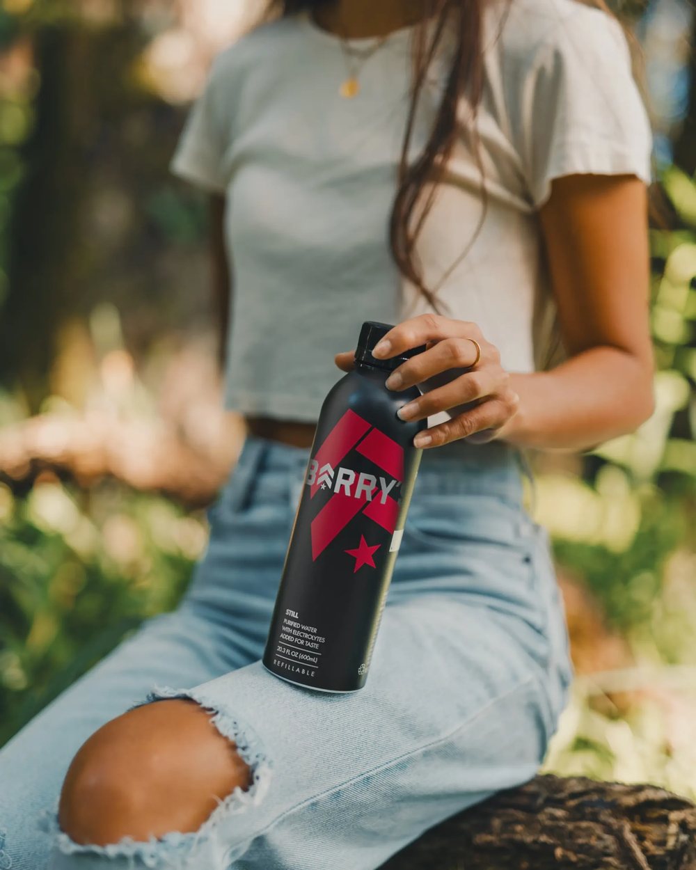 A black PATH bottle co-branded for Barry's, held up in the sun